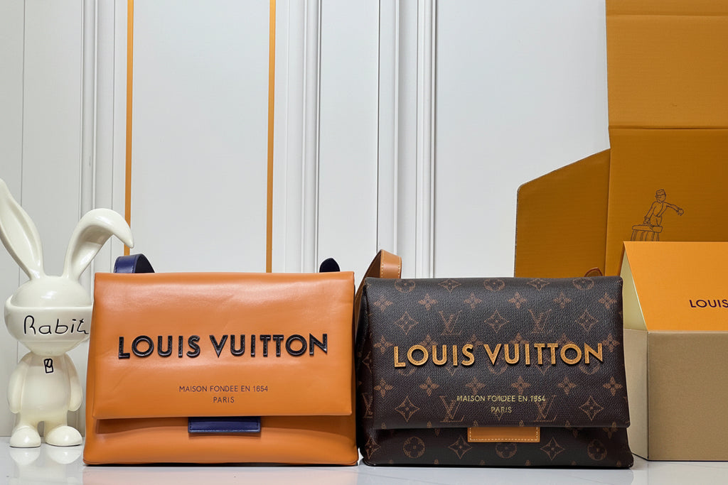 Two Louis Vuitton bags, one orange and one monogrammed, with a box in the background.