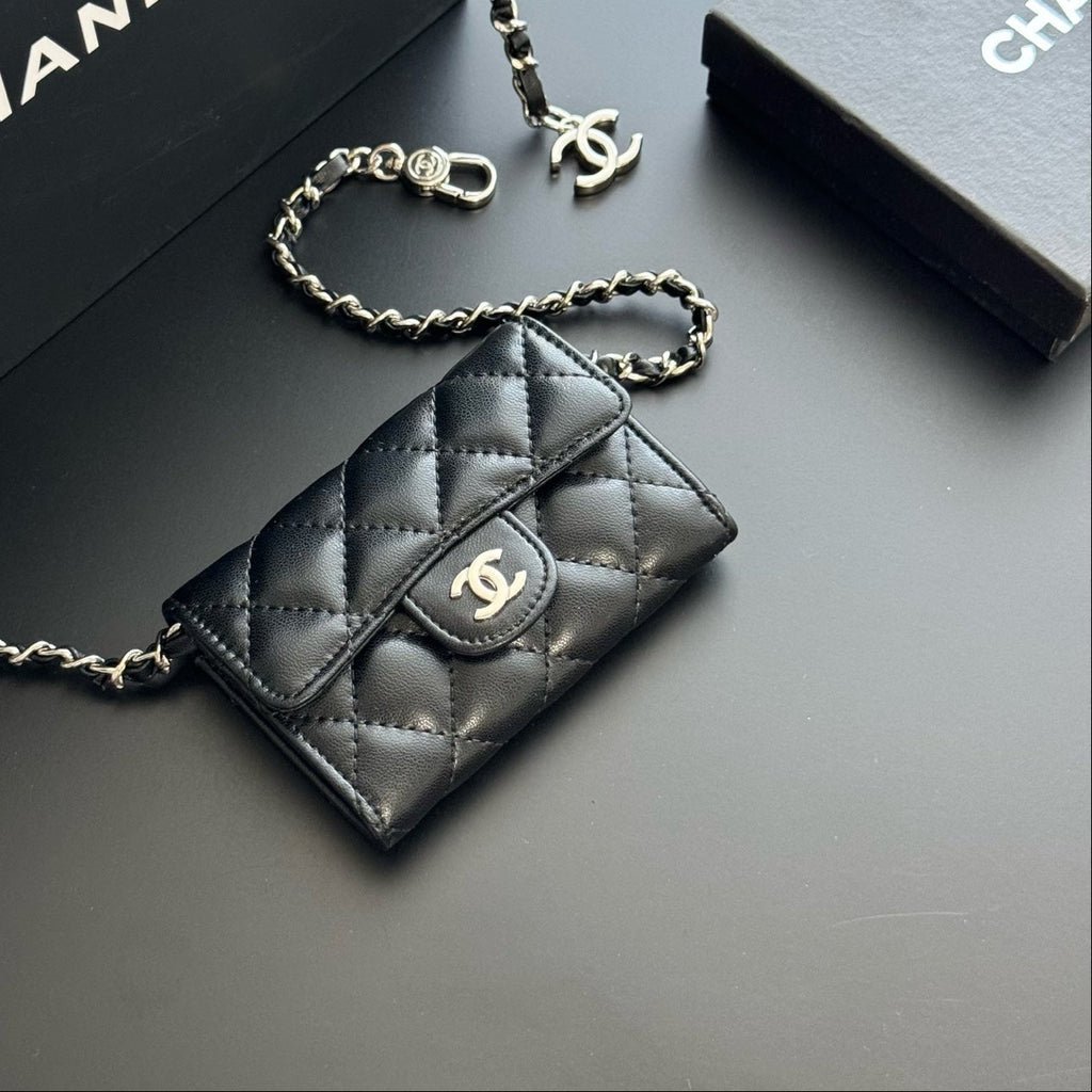 Black quilted handbag with gold chain and Chanel logo on a dark background
