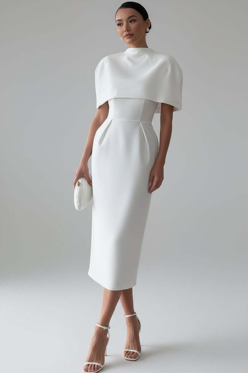 Woman in a white dress standing in a room with wooden flooring and a white wall.