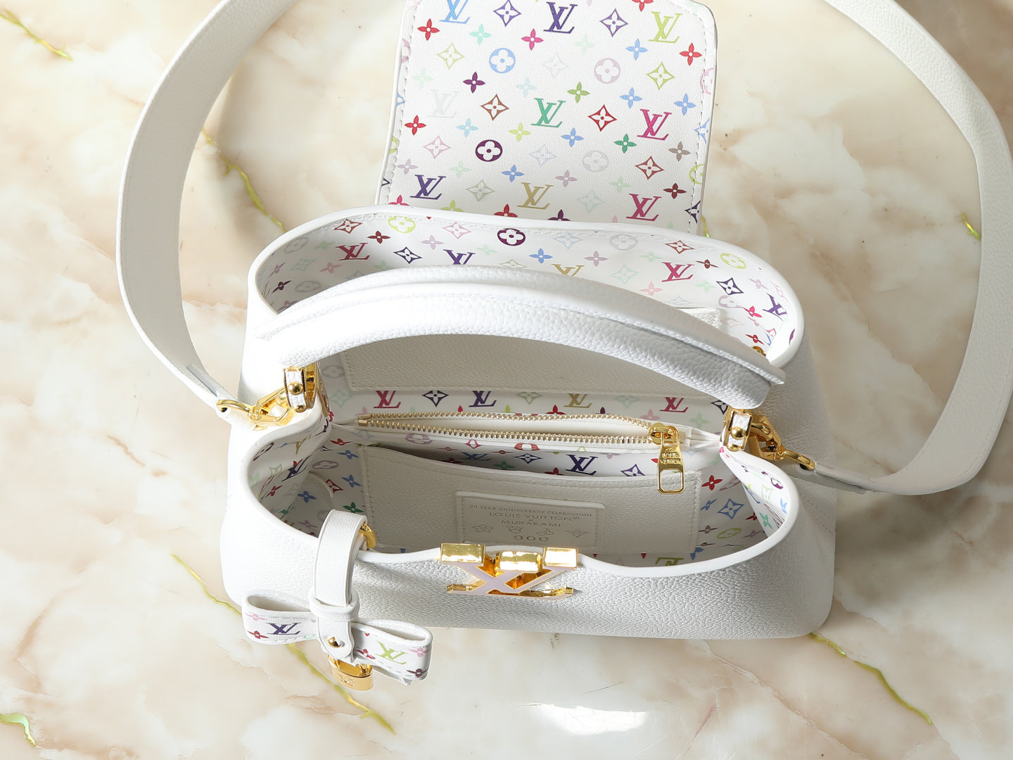 White handbag with multicolor logo pattern on a marble surface