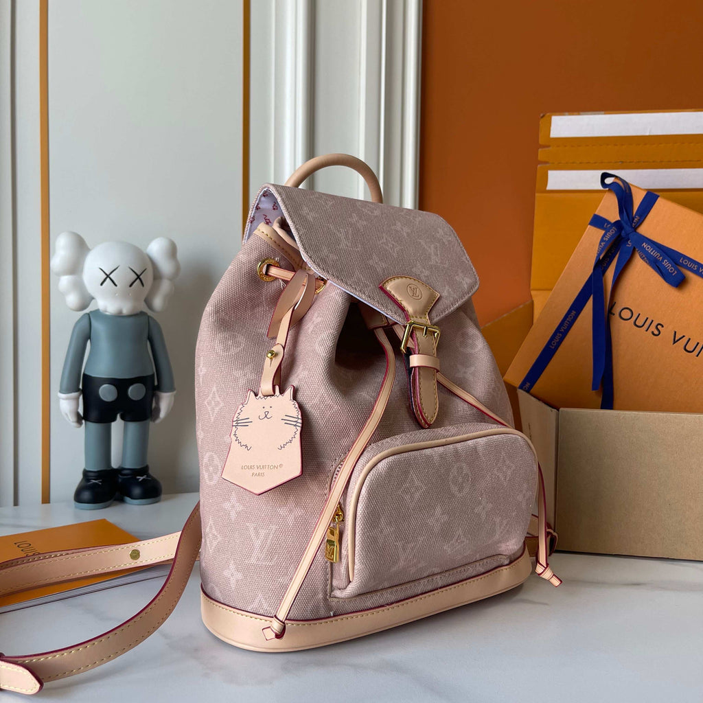 Pink backpack with gold accents on a surface with a KAWS figure and Louis Vuitton box in the background.