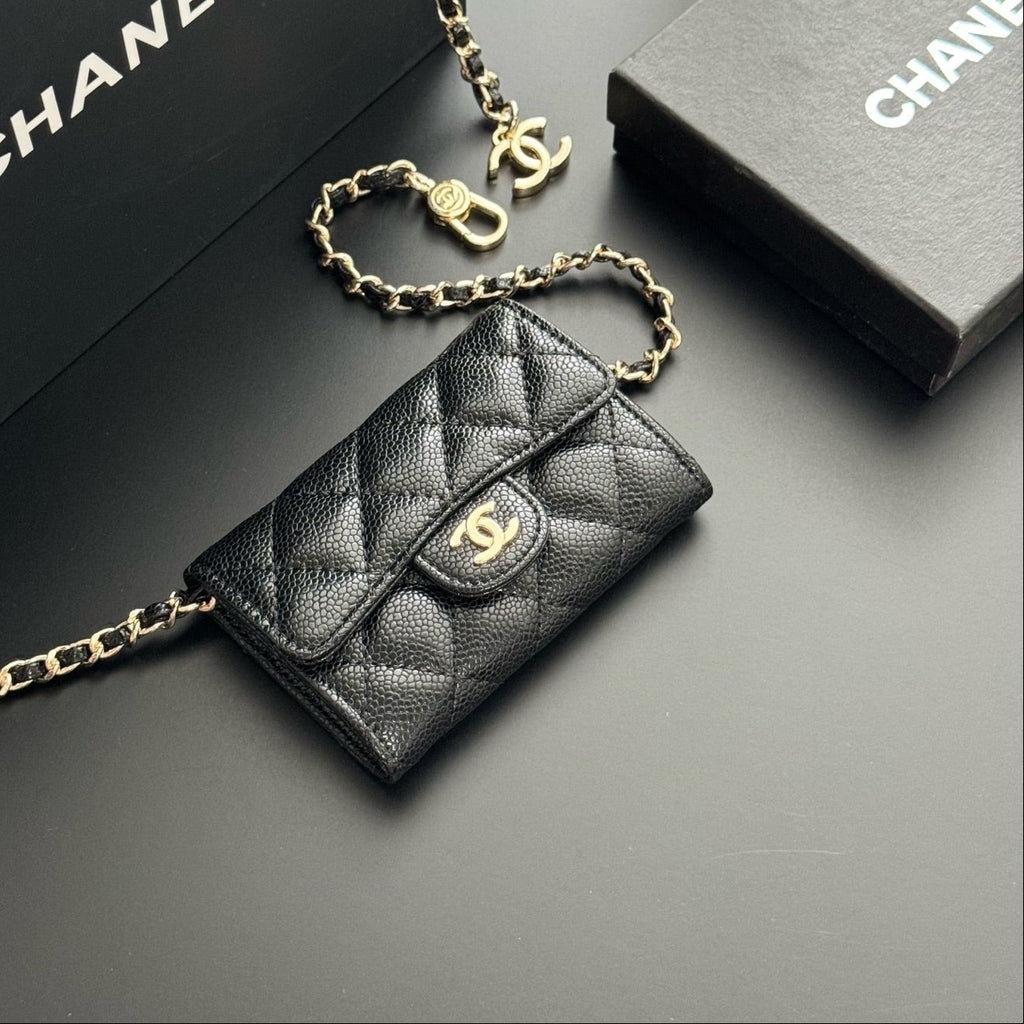 Black quilted handbag with gold chain and Chanel logo on a dark background
