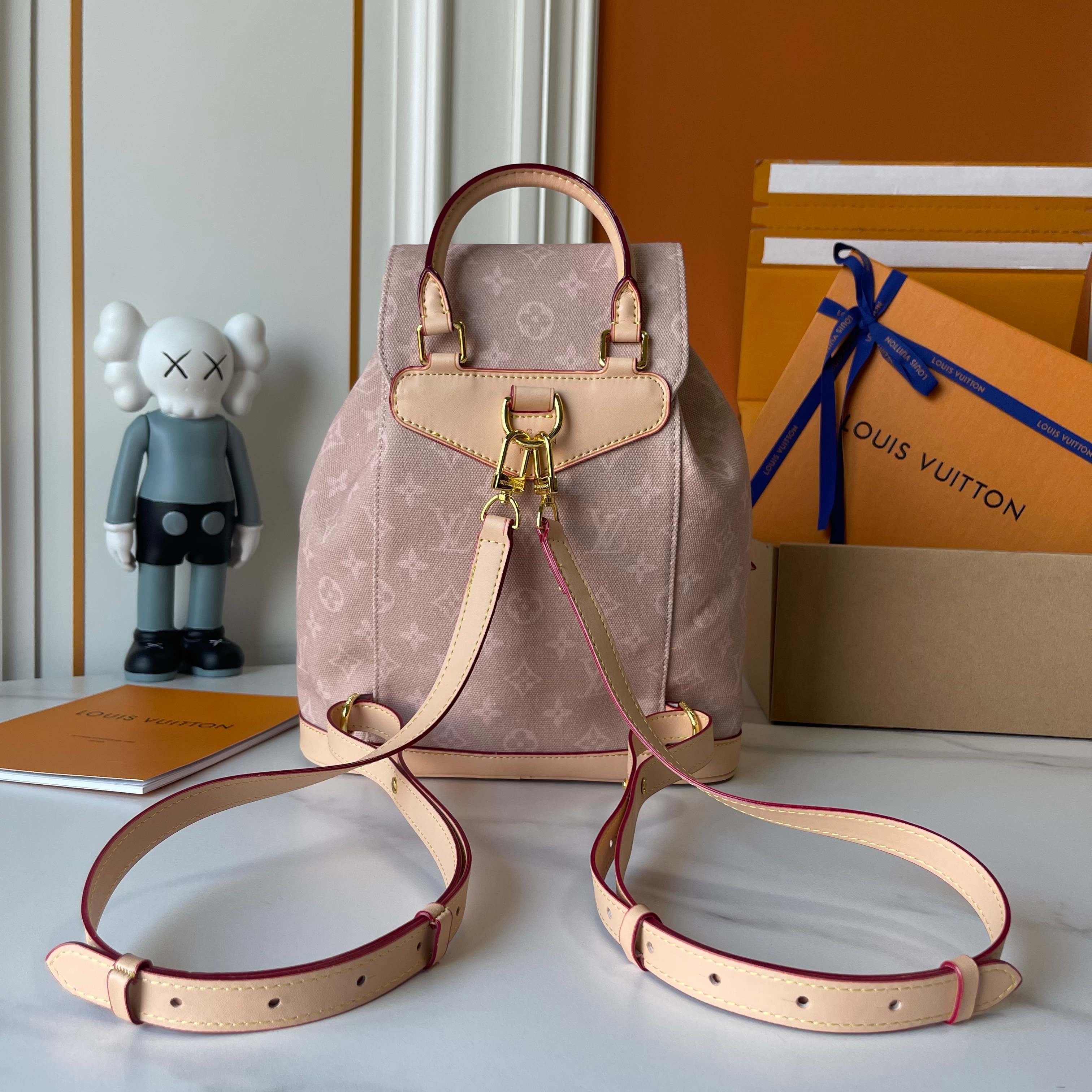 Louis Vuitton backpack with a toy figure and branded box in the background