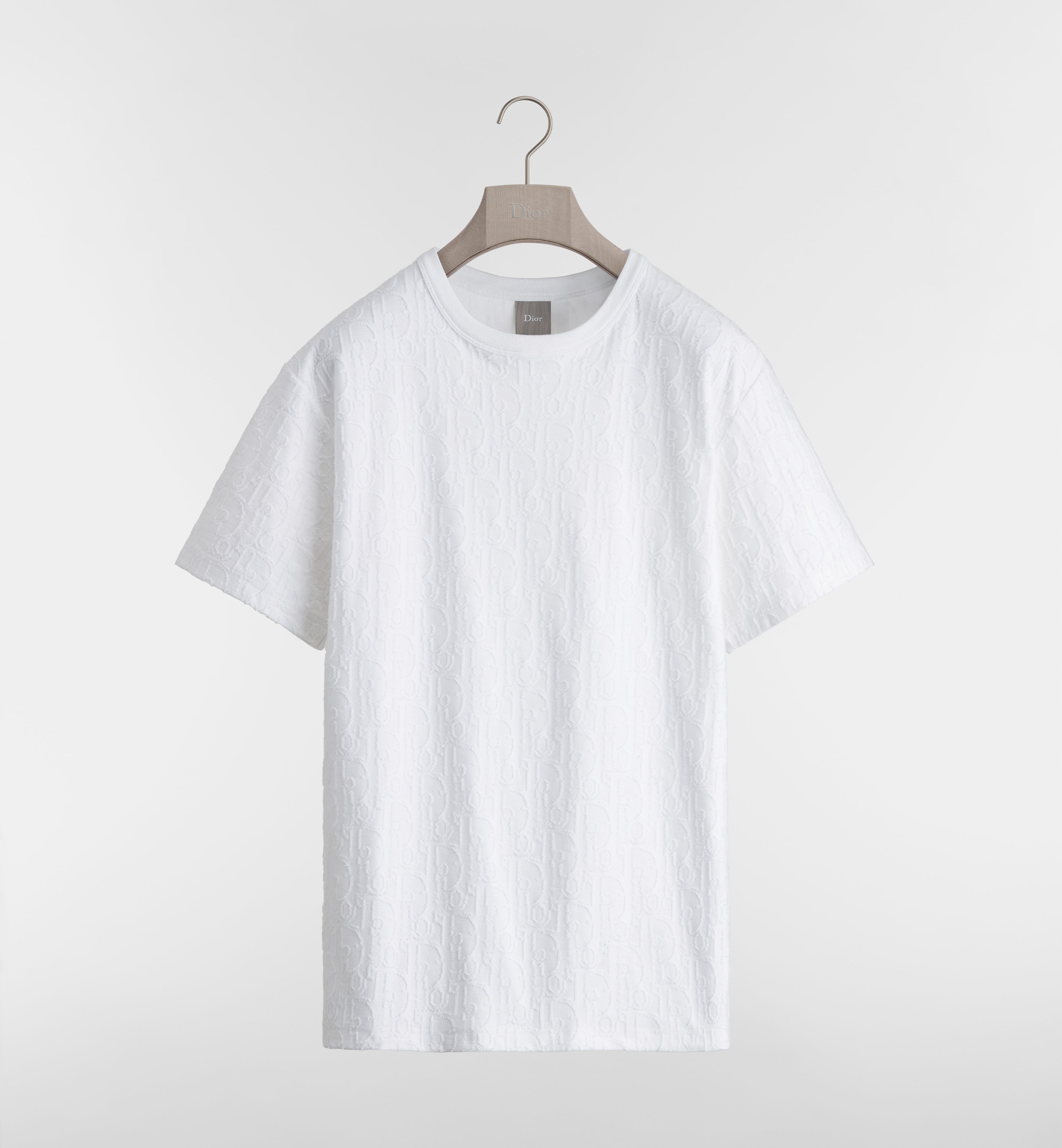 White t-shirt on a hanger against a light gray background