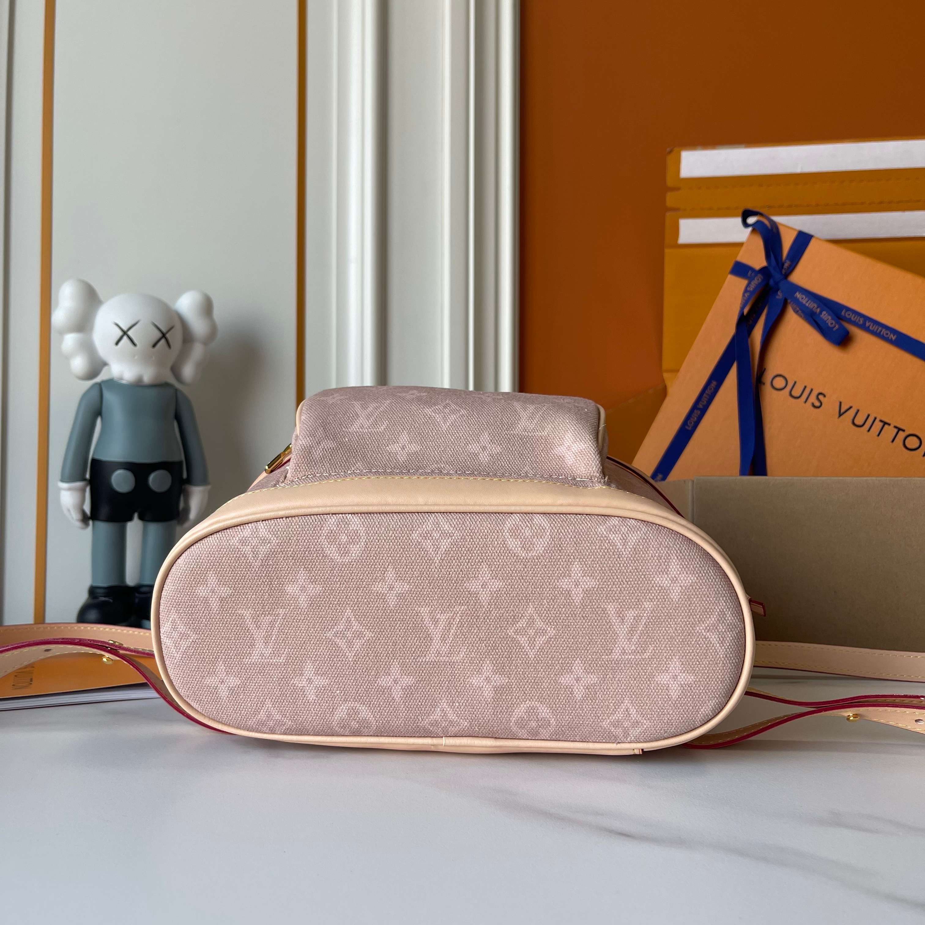 Louis Vuitton monogram handbag with a KAWS figure and Louis Vuitton packaging in the background.