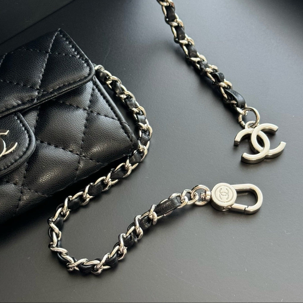 Black quilted handbag with a braided chain strap on a dark surface