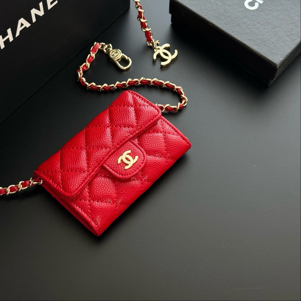 Red Chanel wallet with gold chain on a black background