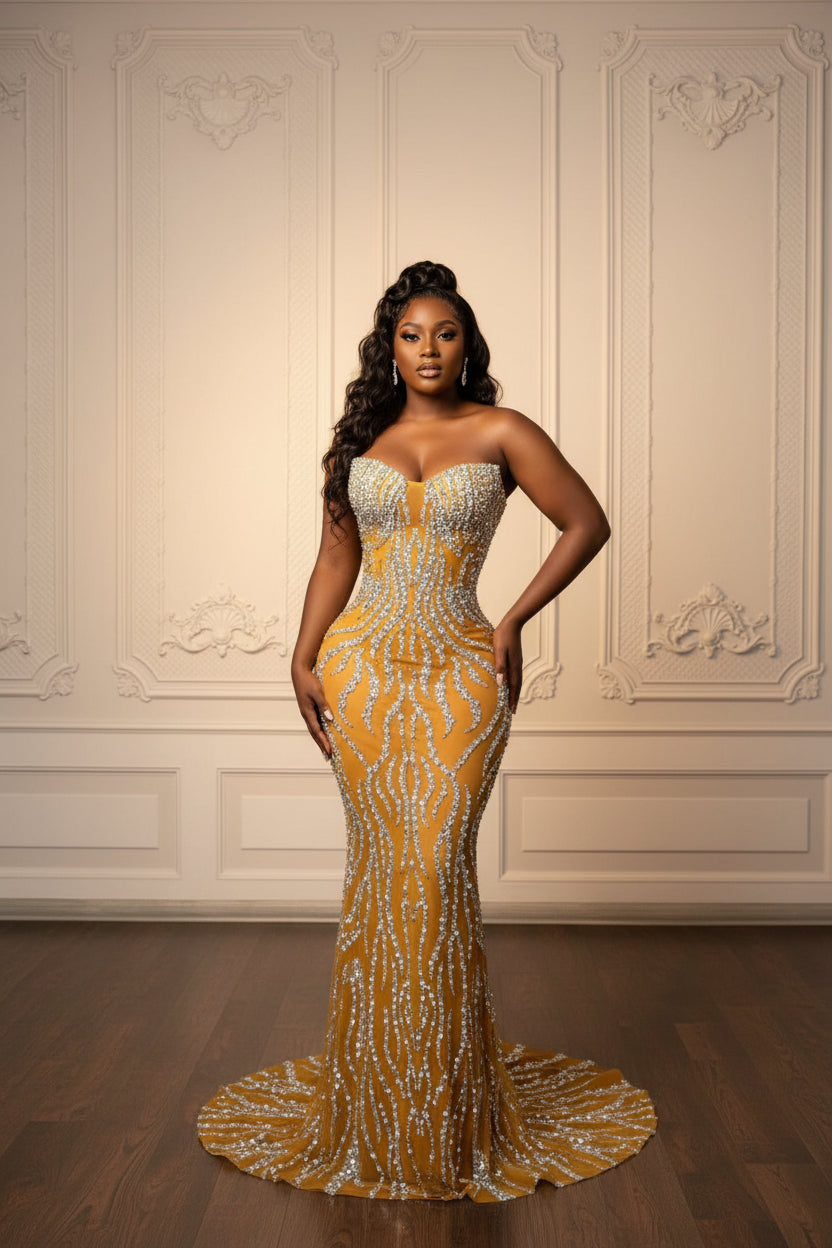 Gold evening gown with intricate design on a mannequin against a decorative wall.