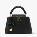 Black handbag with colorful accents and gold hardware on a white background