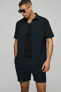 Man wearing a black outfit with sunglasses on a gray background