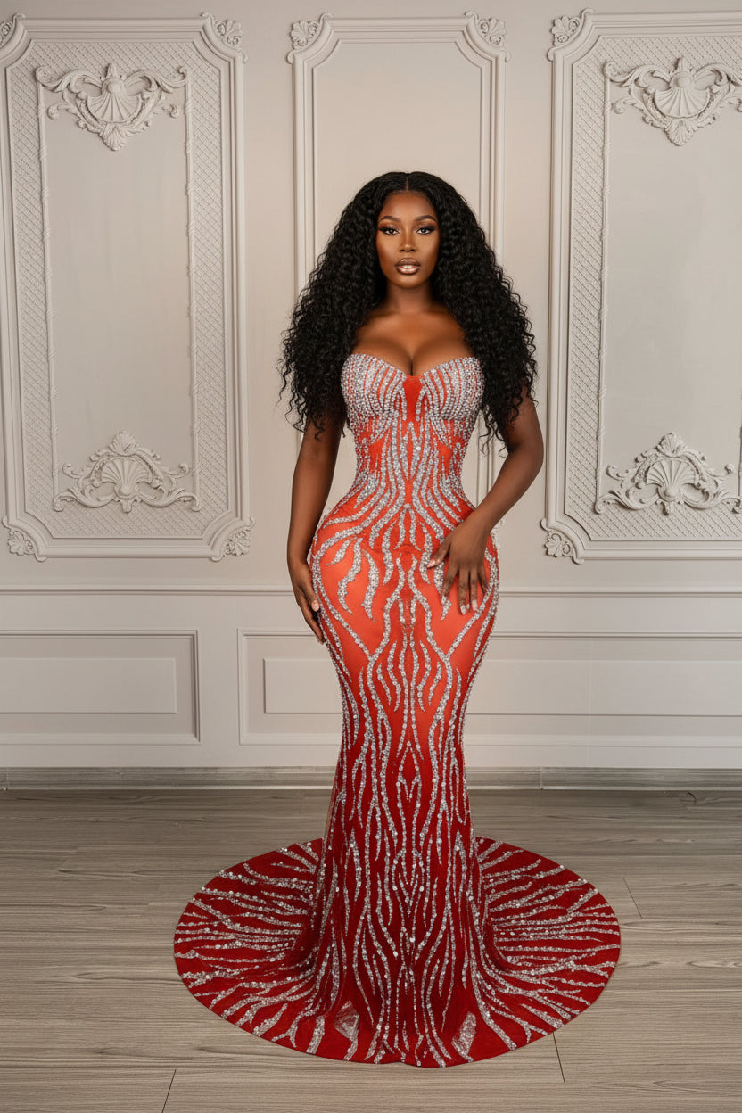 Red evening gown with silver embellishments on a mannequin against a decorative wall.