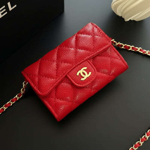 Red quilted handbag with gold chain on a dark surface