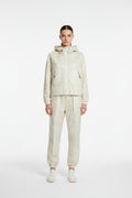 Light-colored pants and jacket on a hanger against a neutral background