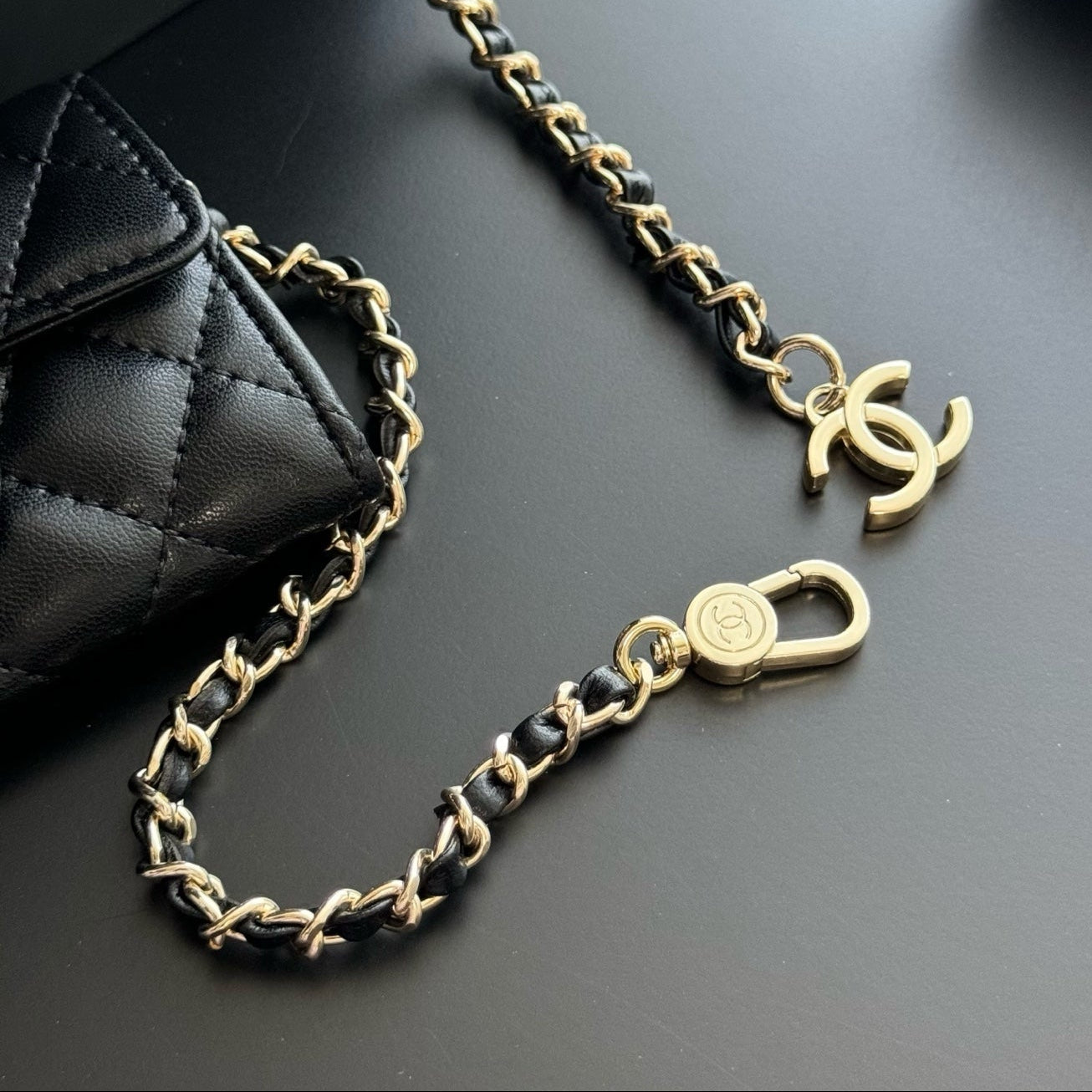 Black and gold chain with a CC logo on a dark surface