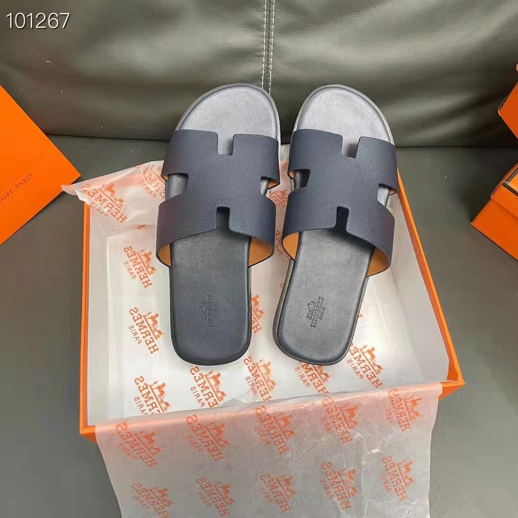 Pair of dark blue slides on Hermes packaging with orange and white logo.